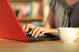 Lady typing on a red laptop